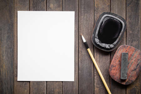 Abstract white paper with bamboo calligraphy brush and inkstone on old wooden table. picture for add text or greeting card chinese new year. Chinese traditional painting textの写真素材