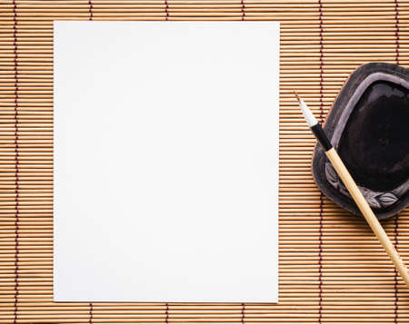 Abstract white paper with bamboo calligraphy brush on bamboo mat background. picture for add text or greeting card chinese new year. Chinese traditional painting text paper.の写真素材