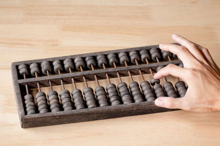 Vintage tone of Man's hands accounting with old abacus and hold electronic calculator. picture...