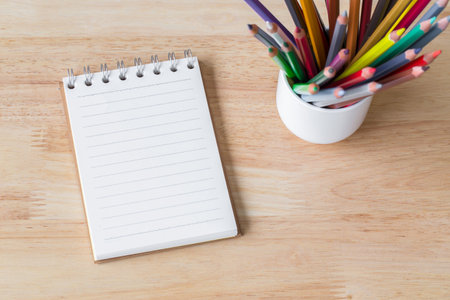 Still life with crayon or pastel Pencil in a glass of white on a wooden floor for background. picture used for add text or education message.の写真素材