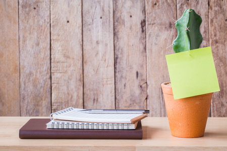 Blank notebook paper with cactus in clay pots on a wooden table. picture used for add text or education message.の写真素材
