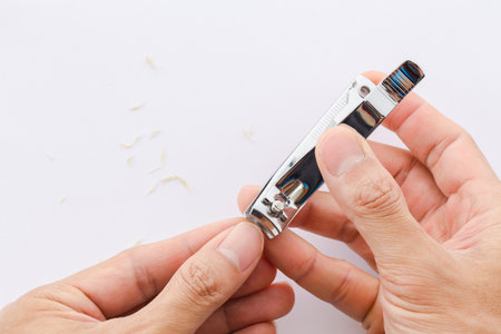 Man cuts his nails with tweezers on a white background. Nail care illustration For their good hygiene.の写真素材