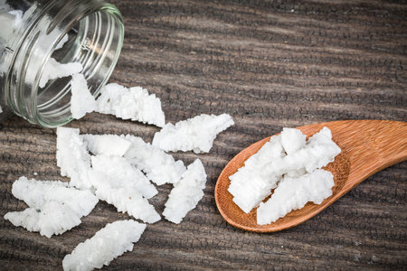 Sea salt in wooden spoon on a wood table. spa saltの写真素材