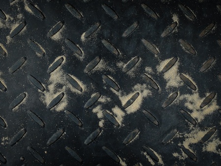 Texture of old black metal sheet with sand on itの写真素材