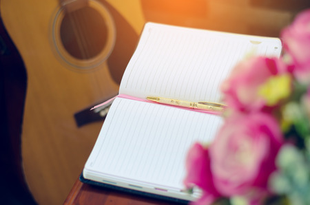 book and yellow pen on table with guitar background