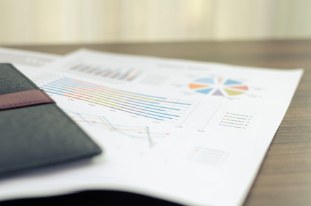 Business documents charts and notebook on wood brown table