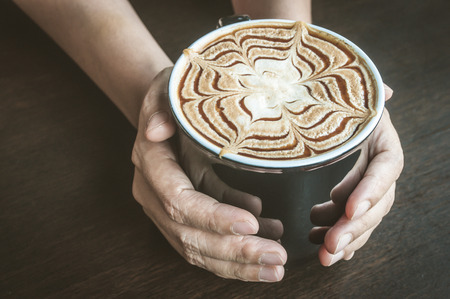 Vintage tone of woman hand serving Caramel Latte Coffeeの写真素材