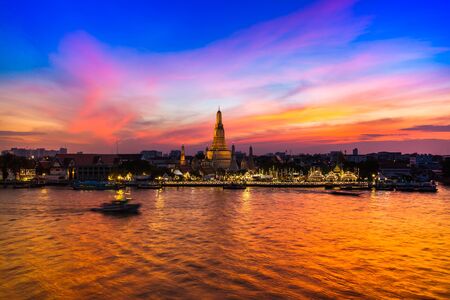 A temple landmark of Bangkok Wat Arun under colorful sunset reflect on chaopraya river