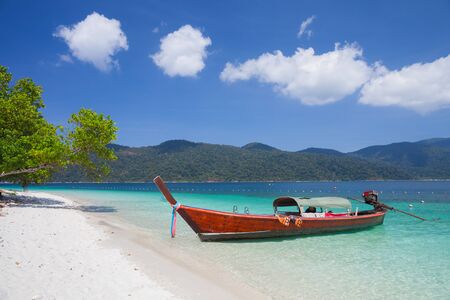 A long tail boat is floating on white sand beach at ocean of Tropicana located at south of Thailandの写真素材