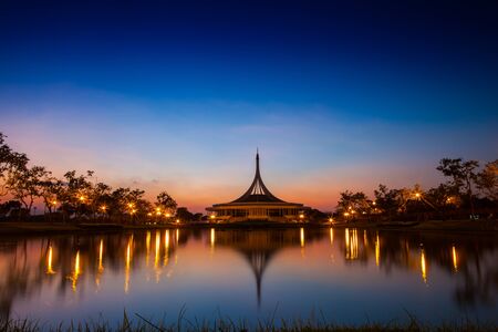 Building at night garden landscape view reflection on water under colorful sky of sunset time located at Rama IX garden Bangkok Thailandの写真素材
