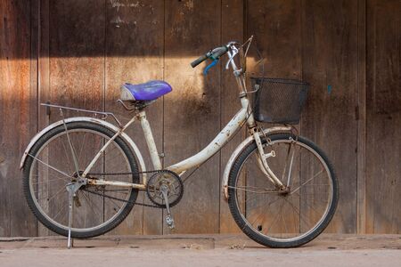 Old white color bicycle parking at front of wooden pattern wall of old house located north east of...