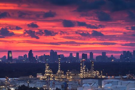 A night landscape view of city and Oil refinery industry under colorful sky at sunset time