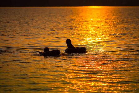 Silhouette of people reflection sunset on water with mountain background location at east of Thailandの写真素材