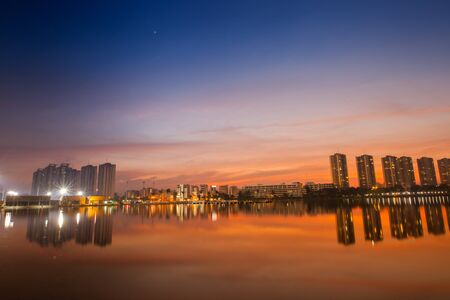 A condominium is reflection on water under colorful sky at sunset timing located at impact arina Bangkok Thailandの写真素材