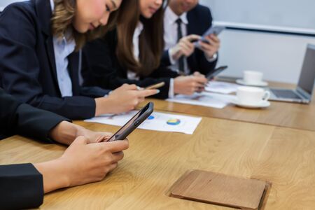Asian business people make a group discussion in meeting room with document and computer putting on wooden tableの写真素材