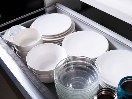 Kitchen furniture with plates stored in drawers, Counter cabinet to store containers Food utensils with ceramic dishes and glass cup.の写真素材