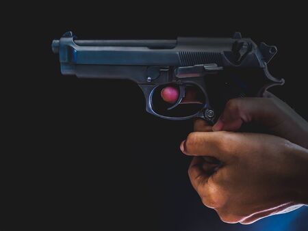 Hand with aiming gun on black background.