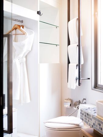 Bathroom interior with white towels on black rail or clothesline, bathrobes hanging in the closetの写真素材