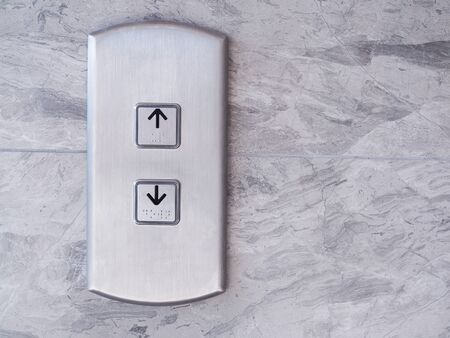 elevator with lift silver button arrow up and down on marble pattern wall.