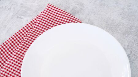 White plate with red cloth on dining table, on dish with copy space for design.