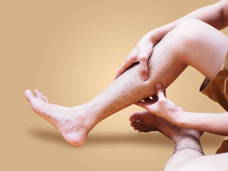 Young man suffering leg pain using hand to massage body to relieve pain, medical symptom and...