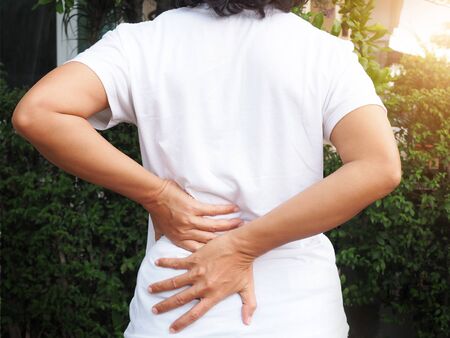 Young Asian Thai women with body aches suffering muscle injury with waist pain and back pain