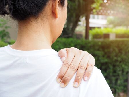 Young Asian Thai women with body aches suffering muscle injury with shoulder pain and back painの写真素材