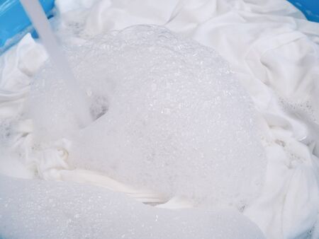 soak white T-shirt in detergent solution, laundry cloth cleaning with washing powder in tub.の写真素材
