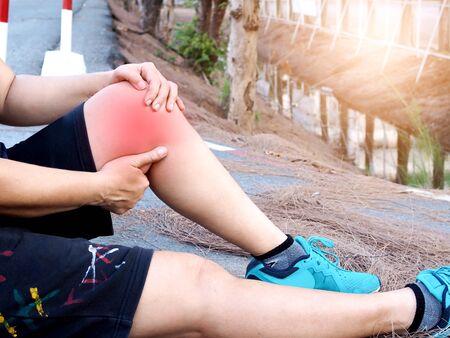 Asian women sit and have knee pain, calf pain, and inflamed leg muscles from jogging.の写真素材