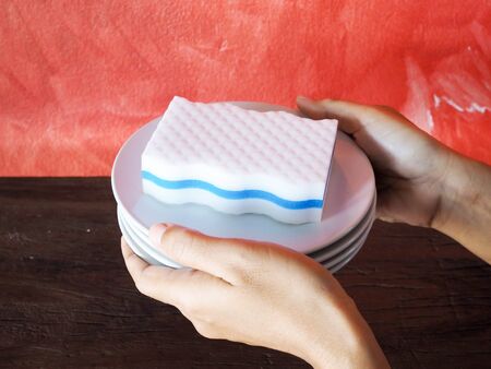 Sponge to cleaning on white ceramic plate in hand.の写真素材