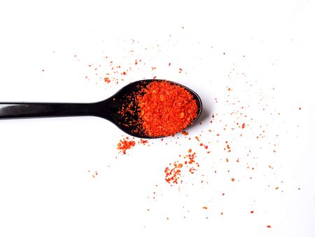 Top view of Black spoon with red cayenne pepper dry powder isolated on white background.の写真素材
