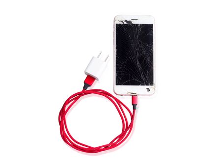 Communication equipment with damaged technology With broken screen mobile phone And red battery charging cable.の写真素材