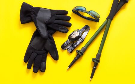 Equipment for trekking, climbing or traveling with walking poles, head lamp, sun glasses, gloves. Isolated on yellow background.の写真素材