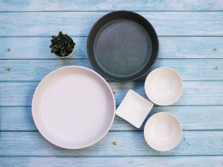Top view of tableware set with ceramics empty round dish plate and bowl cup on wooden table.