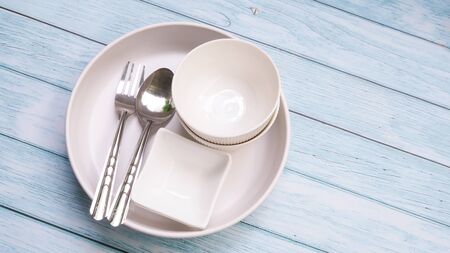 Top view of ceramic round dish plate and cutlery set isolated on wooden tableの写真素材