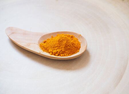 Yellow turmeric powder in wooden spoon, placed on wood backgroundの写真素材