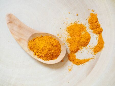 Yellow turmeric powder in wooden spoon, placed on wood backgroundの写真素材