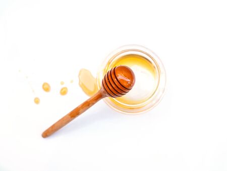  Top view of honey stick in empty honey glass jar with stain of honey isolated on white background.の写真素材