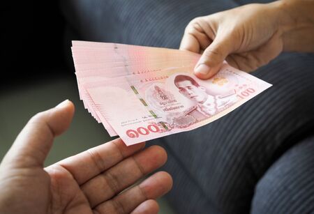submitting Thai baht banknote money of thailand to hand that is waiting receive, Payment, bribery or...