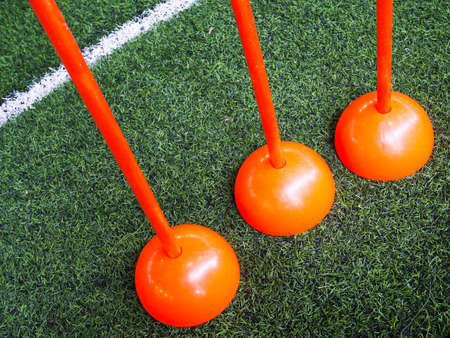 Orange poles equipment on green grass in football field or futsal field