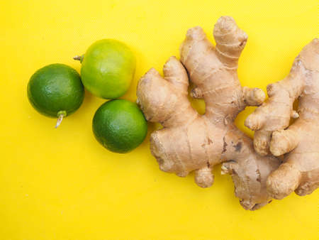 Top view of lime lemons citrus and fresh ginger isolated on yellow background.