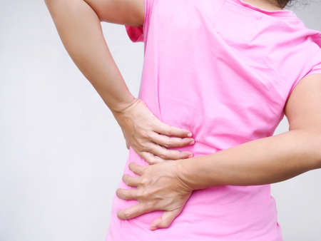 Asian women suffering from back pain  and left lumbar hip pain from illness and health problemsの写真素材