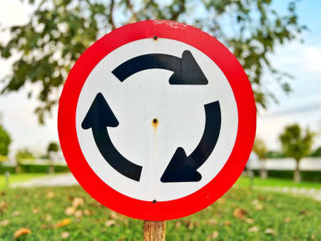 Roundabout traffic sign on the road in the park with trees backgroundの写真素材