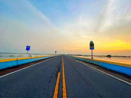 Asphalt road in the middle of the sea with beautiful sky.の写真素材