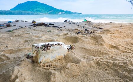 close-up grass bottle and a lot of heaped trash on shoreの写真素材