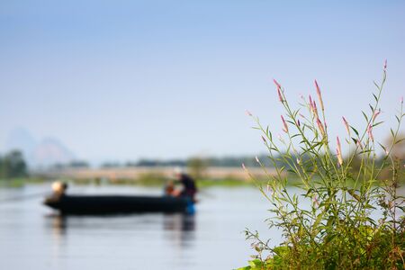 Grass along the river bank against a backdrop of fishermen are fishing .の写真素材