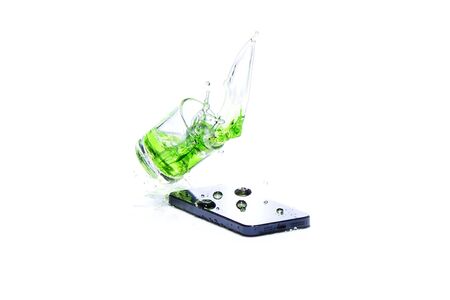 Water in glass spilled smart phone on white backgroundの写真素材