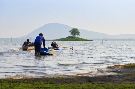 The fisherman are pushing long tail boat to fish in the river.の写真素材