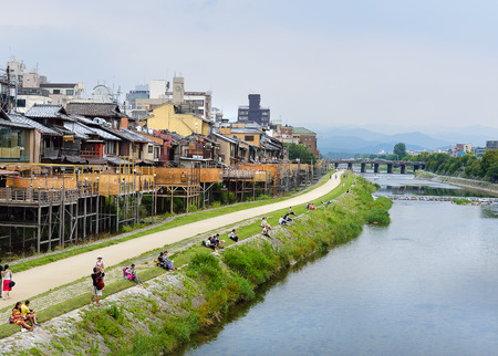 KYOTO, JAPAN - July 24, 2017: As afternoon turns to evening, couples begin to sit on the banks of the Kamo River in Kyoto, Japan, while nearby restaurant verandas begin to fill with customers.のeditorial素材