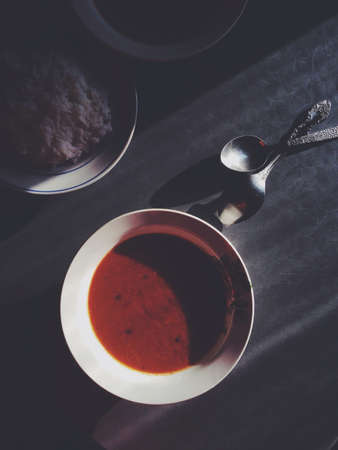 Tomato soup in white plate plain white rice in white plate and two pieces silver spoon on the dark tableの素材